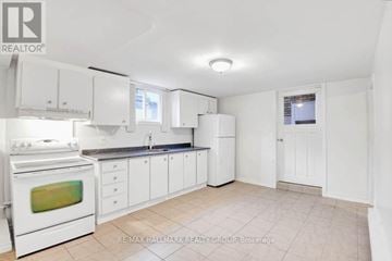 Ottawa apartment for rent - A white kitchen with a stove, cabinets, and a window.