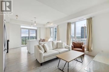 Kitchener condo for rent - A living room with a white couch and a brown chair.