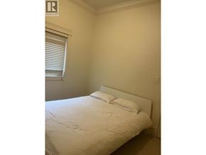 Richmond apartment for rent - A bedroom with a bed, pillows, and a window with blinds.