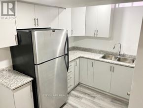 Mississauga (East Credit) apartment for rent - A kitchen with a black refrigerator and white cabinets.