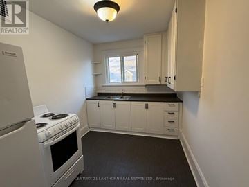 Prince Edward County (Picton Ward) multi-family for rent - A kitchen with white cabinets and a stove top oven.