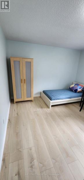 Toronto (Bayview Woods-Steeles) apartment for rent - A bedroom with a bed, wooden floor, and a wardrobe.