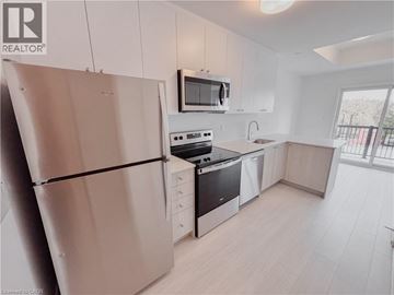 Kitchener condo for rent - A modern kitchen with white cabinets and stainless steel appliances.