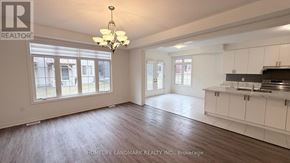 Springwater (Midhurst) apartment for rent - A spacious room with a chandelier and a kitchen area with white cabinets.