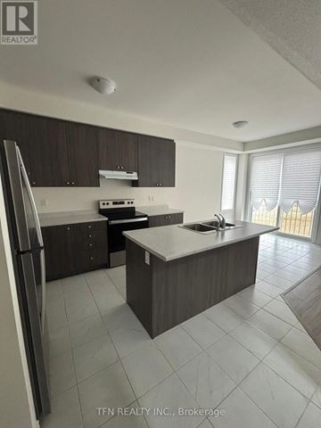 Wasaga Beach apartment for rent - A kitchen with a refrigerator, sink, and stove.