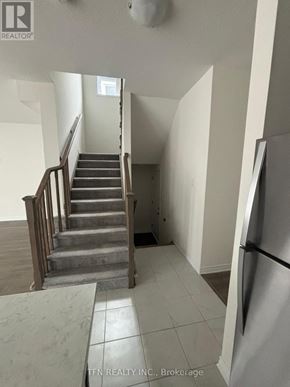 Wasaga Beach apartment for rent - A staircase in a house with a refrigerator on the side.