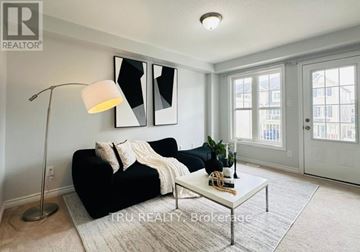 Ottawa townhouse for rent - A well-lit living room with a black sofa and a white floor lamp.