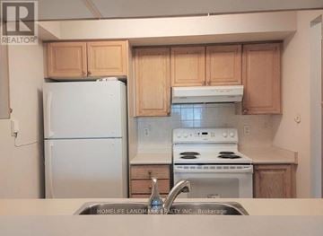 Toronto (Willowdale East) condo for rent - A kitchen with wooden cabinets and a white stove top oven.