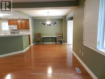 Mississauga (Central Erin Mills) townhouse for rent - A room with wooden floors and a kitchen area with cabinets and a microwave.