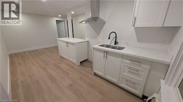 Port Colborne apartment for rent - A kitchen with white cabinets and a wooden floor.