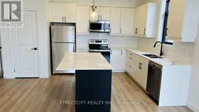 London South (South V) townhouse for rent - A kitchen with a refrigerator, microwave, oven, and sink.