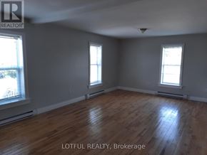 Edwardsburgh/Cardinal apartment for rent - A room with wooden floors and two windows.