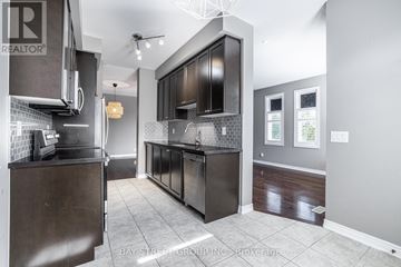 East Gwillimbury townhouse for rent - A modern kitchen with dark wood cabinets and a tiled backsplash.