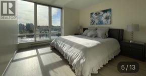 Vancouver apartment for rent - A bedroom with a large bed and a window overlooking a cityscape.