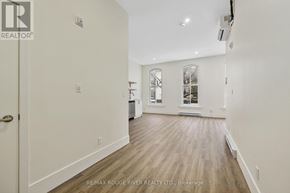 Cobourg apartment for rent - A spacious room with wood flooring and a door on the left.