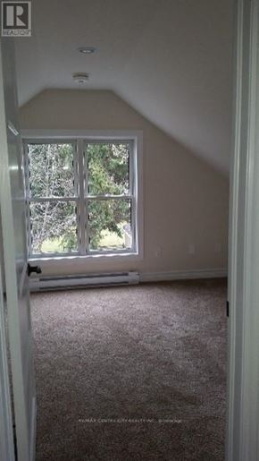 London East (East G) duplex for rent - A carpeted room with a window and a Realty sign on the door.