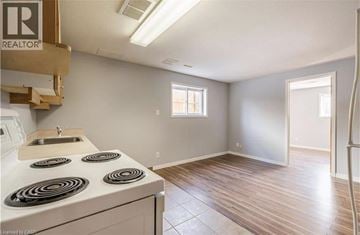 Kitchener apartment for rent - A kitchen with a stove top oven and a sink.