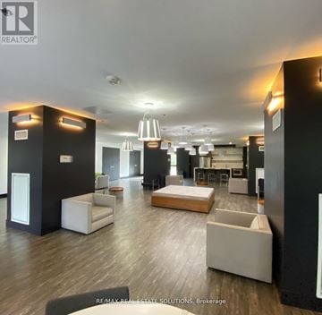 Toronto (South Riverdale) condo for rent - A spacious living room with a white sofa set and a kitchen area in the background.
