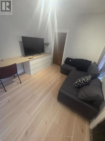 Toronto (Weston-Pellam Park) apartment for rent - A living room with a grey couch and a television on a white desk.
