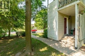 Waterloo townhouse for rent - A white house with a red door is surrounded by greenery.