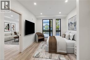 Beamsville condo for rent - A bedroom with a large bed and a flat screen TV mounted on the wall.