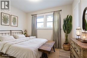 Hamilton apartment for rent - A bedroom with a bed, nightstand, and a plant.
