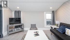 Hamilton apartment for rent - A living room with a black couch, a television, and a window with curtains.