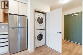 Beamsville condo for rent - A modern kitchen with a stainless steel refrigerator and a washing machine in the laundry room.