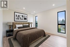 Beamsville condo for rent - A bedroom with a large bed and a framed picture on the wall.
