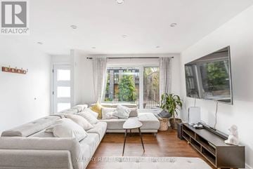 Toronto (South Riverdale) townhouse for rent - A living room with a grey couch and a television on the wall.
