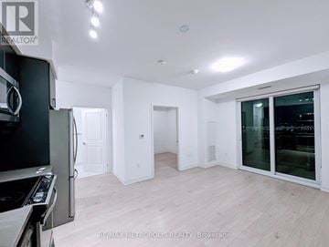 Mississauga (Hurontario) condo for rent - A modern kitchen with white cabinets and a black fridge.