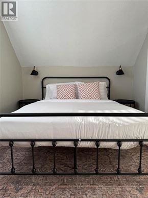 Sarnia apartment for rent - A bed with a white sheet and two pillows with a black metal frame.