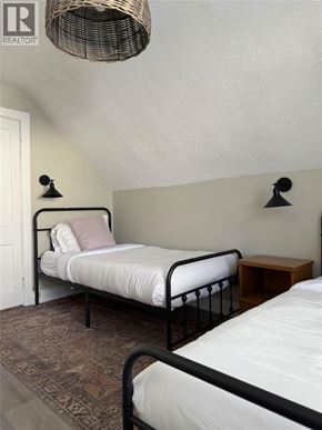 Sarnia apartment for rent - A bedroom with a bed and a wicker lamp.