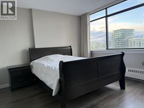 Richmond apartment for rent - A bedroom with a large bed and a window overlooking a cityscape.