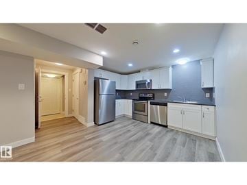 Edmonton apartment for rent - A kitchen with white cabinets and a wooden floor.
