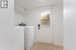 Toronto (Dovercourt-Wallace Emerson-Junction) apartment for rent - A white door with a black handle is in a room with a washing machine and a dryer.