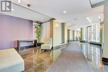 Ottawa condo for rent - A spacious living room with a grey sofa and a white armchair.