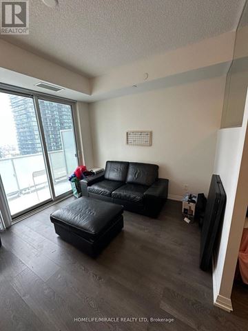 Toronto (Mount Pleasant West) house for rent - A black leather sofa and ottoman in a living room with a flat screen TV.