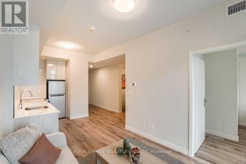 Kitchener condo for rent - A living room with a couch and a kitchen area in the background.
