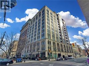 Hamilton condo for rent - A tall building with many windows is located on a street corner.