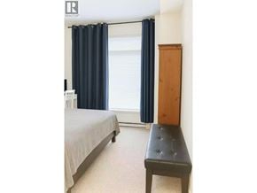 Vancouver apartment for rent - A bedroom with a bed, a bench, and a window with curtains.