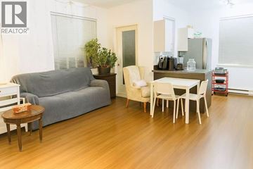 Vancouver apartment for rent - A living room with a grey couch, a white chair, and a wooden coffee table.