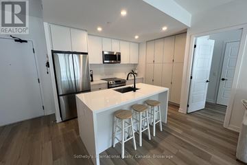 Innisfil condo for rent - A kitchen with white cabinets and a white island with stools.