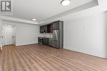 St. Catharines (Oakdale) townhouse for rent - A spacious room with a kitchenette and wooden flooring.