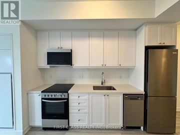 Clarington (Bowmanville) condo for rent - A kitchen with white cabinets and a black microwave above the stove.