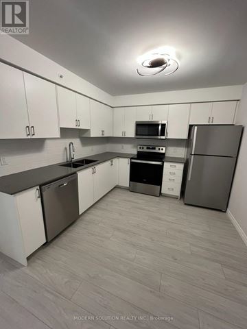 Kitchener condo for rent - A kitchen with white cabinets and a grey refrigerator.