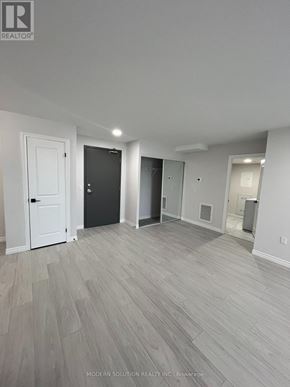 Kitchener condo for rent - A spacious room with light grey flooring and white walls.