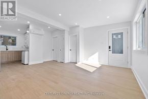 Ottawa multi-family for rent - A spacious room with wooden flooring and white walls, with a door on the right side.