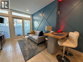 Windsor condo for rent - A living room with a grey couch, a white chair, and a wooden desk.
