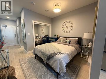 Windsor condo for rent - A bedroom with a large bed and a clock on the wall.